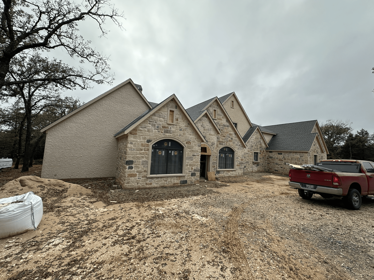 New stone and brick home on a job site with a red work truck out front