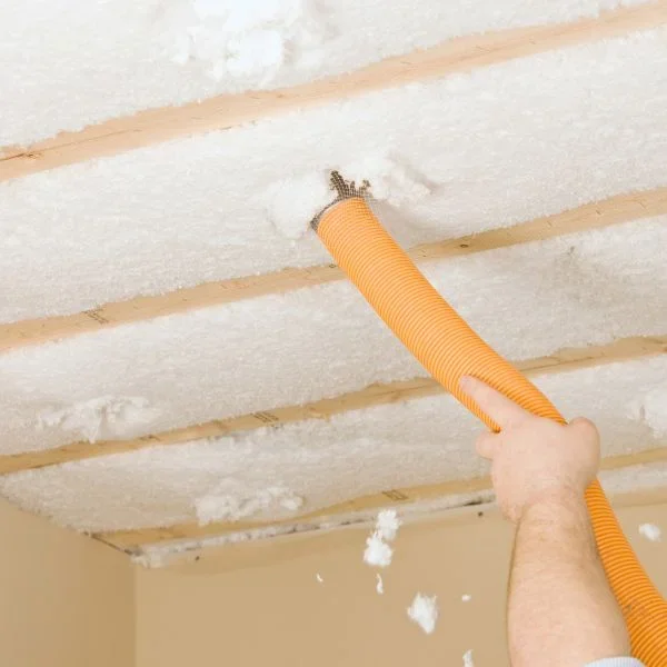 Installer spraying foam insulation between ceiling joists