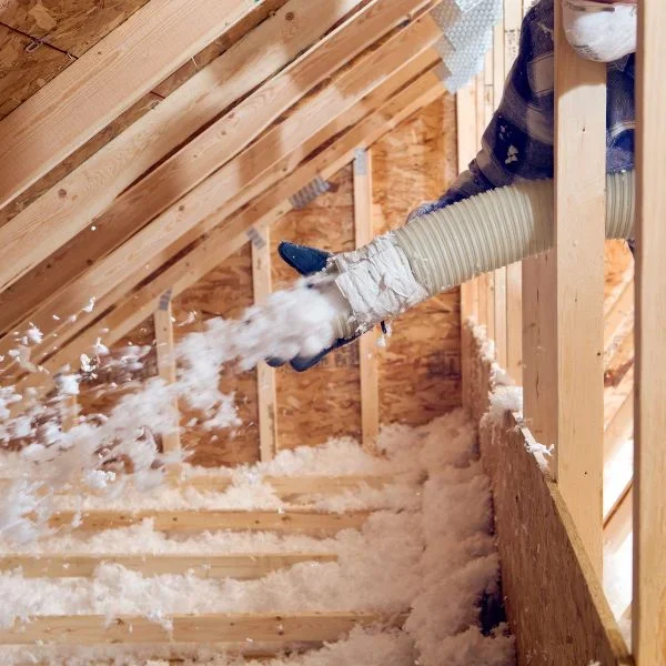 Installer blowing loose-fill insulation into an attic