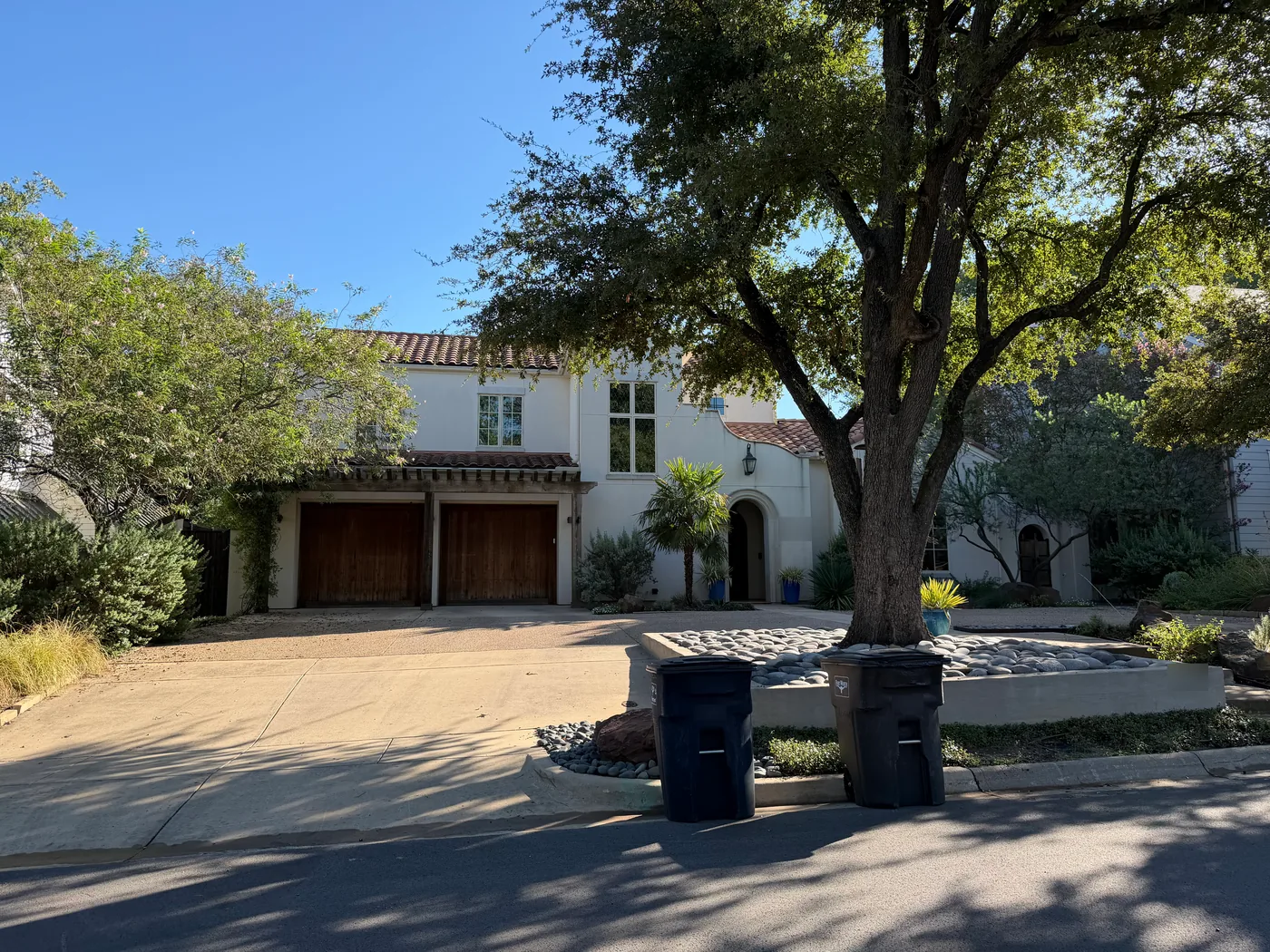 Two-story stucco home with a clay tile roof and wood garage doors in Crestwood, Fort Worth, after an attic insulation retrofit